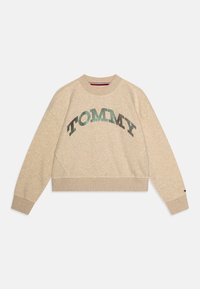 Beige zkrácená mikina s kulatým výstřihem, na přední straně zdobená třpytivým nápisem "TOMMY" z černých a zelených flitrů.