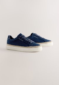 Blå denim sneakers med en tekstureret overflade, hvide gummisåler og kontrastsyning. Har klassisk snørelukning og lavt snit.