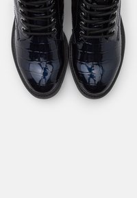 Námořnické lakované kozačky nad kotníky s krokodýlím vzorem, kulatou špičkou, černými tkaničkami a texturovanou podrážkou, s elegantním, vysoce lesklým povrchem.