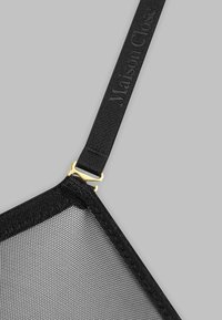Soutien-gorge en maille noire avec une forme géométrique, doté d'un fermoir doré et de bretelles texturées embossées avec "Maison Close."