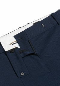 Pantaloni sartoriali blu navy in tessuto testurizzato. Presentano chiusura con bottone, zip frontale e una fodera bianca con accenti decorativi.