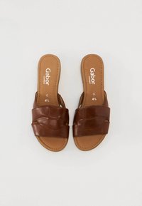 Sandali scivolati in pelle marrone con cinturini intrecciati, apertura sul retro, soletta imbottita e dettagli cuciti. Logo del produttore visibile.
