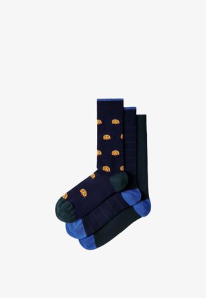 Tres pares de calcetines de colores oscuros, uno azul marino con pequeñas caras de perros naranjas, uno oscuro a rayas y uno verde oscuro sólido con talones y dedos azules.