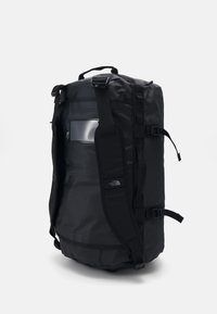Sac de sport noir en matériau durable et résistant à l'eau. Doté de bretelles ajustables, d'une poche latérale et d'un logo. Design structuré et cylindrique.