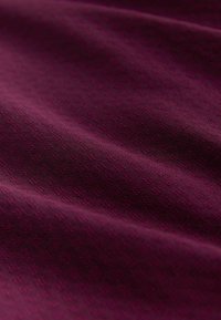 Bordowy materiał o gładkiej fakturze, z delikatnym geometrycznym wzorem. Tkanina jest elastyczna i prezentuje miękkie, bogate odcienie kolorów.