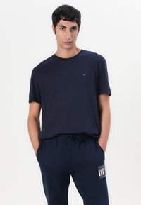 Marineblauwe katoenen T-shirt met ronde hals, korte mouwen en een klein geborduurd logo op de borst, gecombineerd met bijpassende marineblauwe sweatpants.