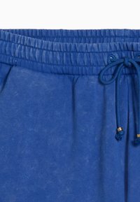 Pantaloni corti blu con coulisse e vita elasticizzata, realizzati in tessuto leggero. Presentano terminali in oro sulla coulisse.