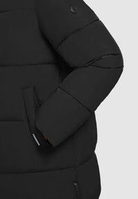 Giacca a puffer nera con design trapuntato; presenta una tasca con zip e una toppa con logo sulla spalla; texture liscia e isolamento spesso.