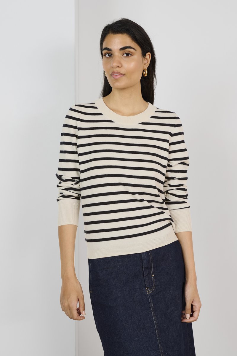Pull crème avec des rayures horizontales noires, col rond, poignets côtelés, porté avec une jupe en denim foncé, texture lisse, coupe décontractée.
