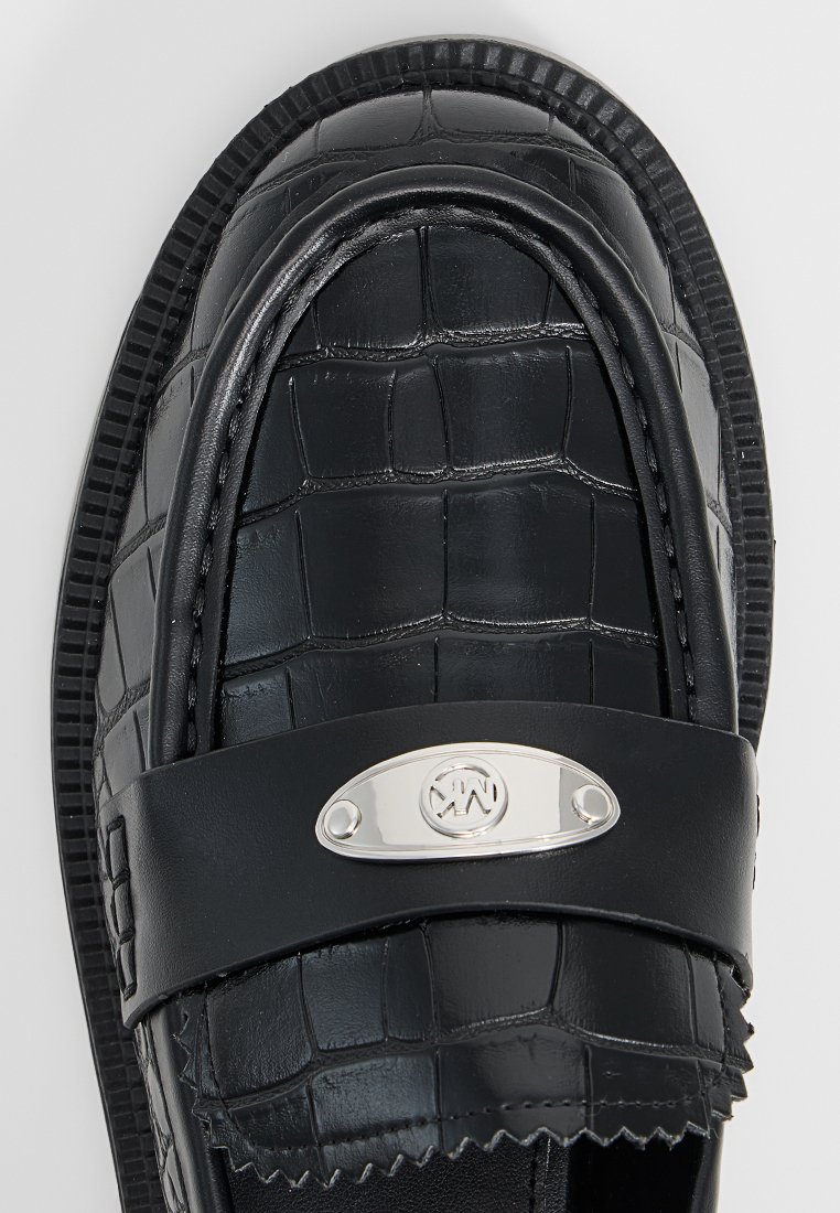 Schwarze Loafers aus geprägt kroko-muster Leder, ausgestattet mit einer silbernen Logo-Plakette und einer strukturierten Gummisohle.