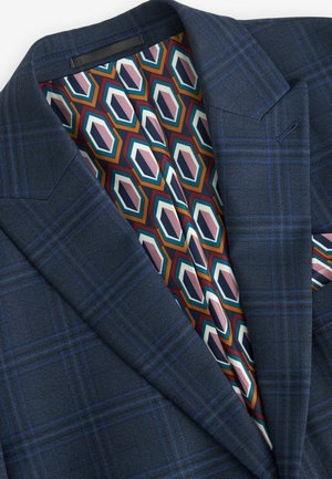 Dark blue plaid blazer with a textured fabric. Interior features a geometric pattern in orange, teal, pink, and cream on a dark backdrop.