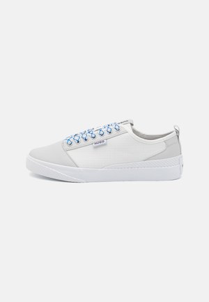 Weiße Low-Top-Sneaker mit blauen und weißen Schnürsenkeln, strukturierten Seitenpaneelen und einem "HUGO"-Logoetikett an der Seite, vor einem hellen Hintergrund.