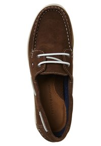 Zapato de ante marrón con cordones blancos, costuras en contraste y una plantilla perforada. Presenta una forma redondeada y una parte superior texturizada.