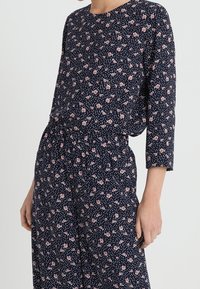 Abito navy con maniche a 3/4, decorato con piccoli motivi floreali rosa, caratterizzato da una vestibilità comoda e un tessuto morbido e leggero.