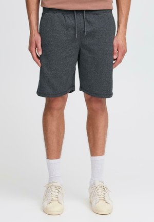 Shorts en tricot gris avec une taille élastique et un cordon de serrage. Comprend des poches latérales et une coupe décontractée, se terminant juste au-dessus des genoux.