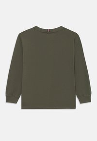 Olivengrønn langermet uformell T-skjorte med ribbestrikkede mansjetter og en liten rød, hvit og blå brodert detalj på baksiden av halsen.