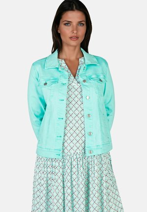 Veste en jean aqua clair avec poches avant et boutons argentés, associée à une robe à motifs avec des diamants en turquoise et blanc.