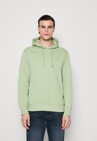 Sudadera verde clara con bolsillo canguro, capucha con cordones y logo de la marca en relieve en el pecho. Tejido suave y liso con puños acanalados.