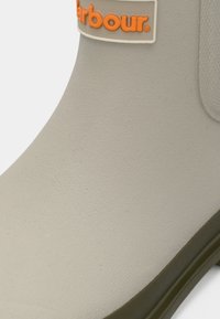 Ανοιχτό γκρι λαστιχένια μπότα με πορτοκαλί λογότυπο "Harbour", υφή, καμπυλωτό επάνω μέρος και σκούρα πράσινη σόλα. Κατάλληλη για υγρές συνθήκες.