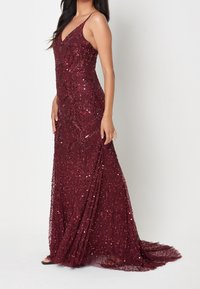 Valkoinen samettimekko, jossa on istuva korsetti, V-muotoinen kaula-aukko ja spaghetti-henkseleitä. Sisältää monimutkaista helmiäyksityiskohtaa ja virtaavan takapanssarin.