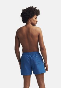 Blå simshorts i lättviktsmaterial, med elastisk midja och bakficka. Slät struktur med en enfärgad design.