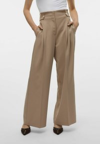 Højttaljede beige bukser med plisseringer, sidelommer og doble knapper ved taljen. Glat tekstur og bred ben design.