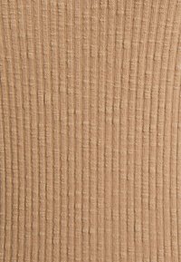 Tessuto a coste in beige caldo con linee verticali e motivi testurizzati, caratterizzato da un aspetto morbido simile a quello della maglia e da sottili accenti in rilievo.