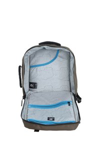 Zaino verde oliva scuro con un interno a fantasia grigia, dotato di cerniere blu e scomparti per l'organizzazione. Design spazioso e funzionale.