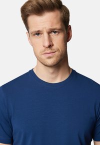 Granatowa, krótko rękawowa koszulka wykonana z miękkiego materiału, z okrągłym dekoltem i gładką fakturą. Brak widocznych wzorów lub logo.