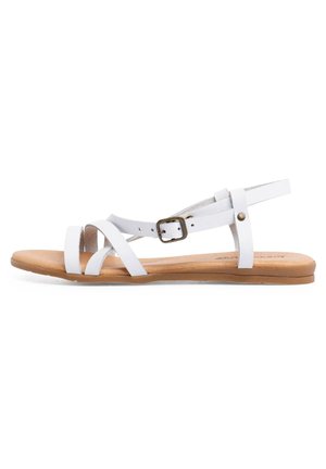 Weißes Leder-Sandalen mit überkreuzten Riemen, verstellbarem Knöchelverschluss und flacher brauner Sohle. Glatte Textur und minimalistisches Design.
