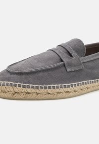 Grå canvas slip-on sko med rund tå, udstyret med en dekorativ rem og en sål af jute reb for ekstra tekstur og detaljer.