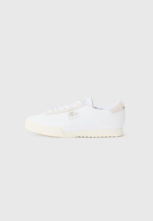 White low-top sneaker with beige sole and heel tab, lace-up front, and small silver brand logo on side.