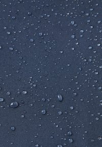 Waterproof navy fabric with a textured surface, featuring numerous droplets of water across the material, highlighting its water-resistant properties.