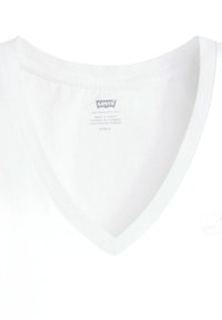 Camiseta de algodón blanco con diseño de cuello en V. Presenta una textura suave, un estilo minimalista y una etiqueta de cuidado cosida en el interior del cuello.