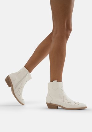 Botas de tobillo de cuero blanco con cremallera lateral, diseños florales bordados y un tacón bajo y apilado. Textura suave y elementos de diseño delineados.