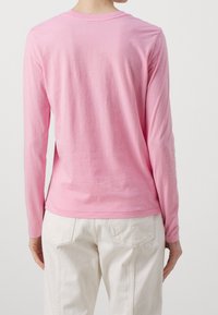 Långärmad skjorta i mjuk rosa bomull, med rundad halsringning och figursydd design med rak fåll. Justerbara ärmknappar.