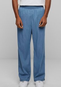 Lysblå, brede bukser i et blødt, denim-lignende stof med elastisk talje. Har sidesømme og en afslappet pasform.