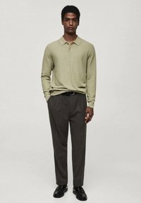 Light green long-sleeve polo shirt with a collar, paired with dark grey tailored trousers and black shoes. Simple design, smooth texture.