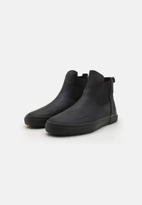 Black leather ankle boots with elastic side panels, rounded toe, and smooth texture. Thick black rubber sole with stitching details.