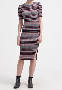 Ribbade stickade klänning med horisontella ränder i rött, grått och vitt. Korta ärmar, längd till mitt på vaden, sidospalt, kombinerad med svarta ankelstövlar.