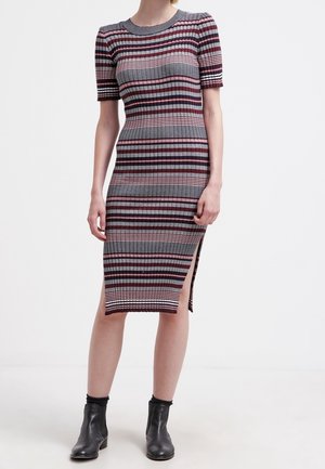 Robe en tricot côtelé avec des rayures horizontales en rouge, gris et blanc. Manches courtes, longueur mi-mollet, fente sur le côté, associée à des bottines noires.
