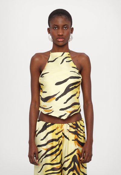 Haut halter jaune avec des rayures de tigre noires et orange, fabriqué dans un tissu lisse et léger, avec un ourlet arrondi et un dos ouvert.