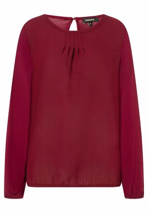 Bordeauxfarbene Bluse mit langen Ärmeln und Rundhalsausschnitt, Falten an der Vorderseite, Schlüssellochdetail im Rücken und elastischen Manschetten. Glatte Stoffoberfläche.