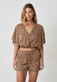 Braun gemusterter Cropped-Top mit tiefem V-Ausschnitt und kurzen Armen, kombiniert mit passenden Shorts mit elastischem Bund. Beides aus leichtem Material.