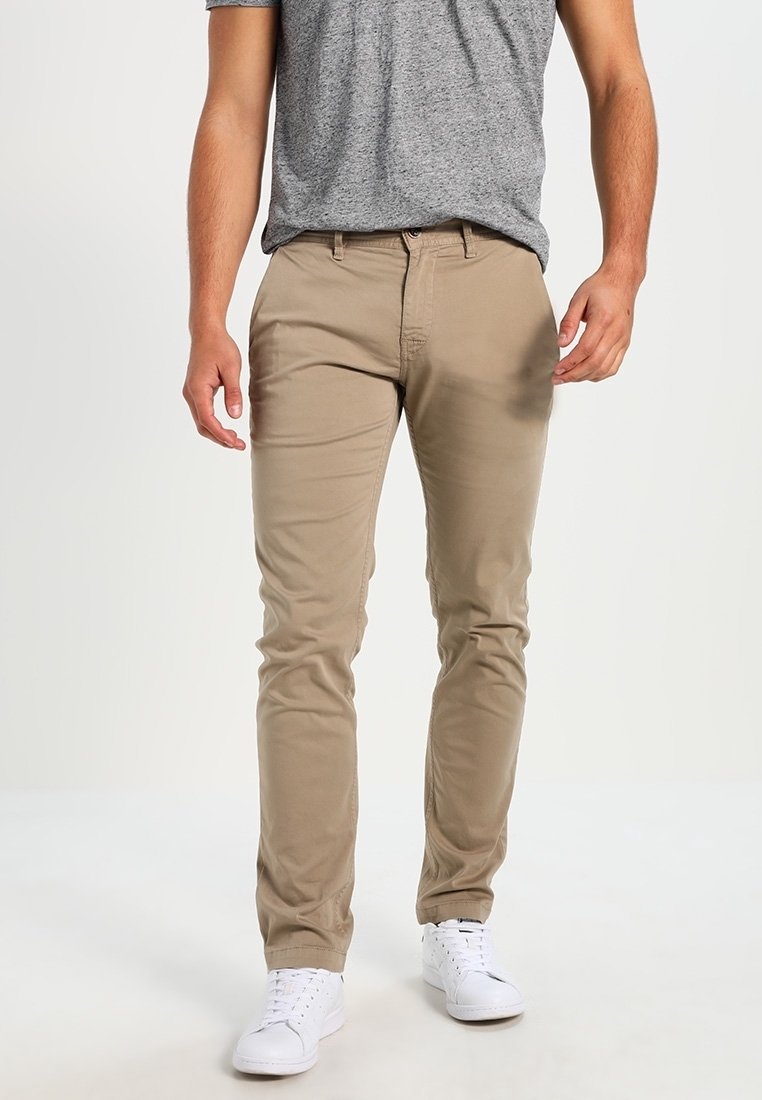 Beige bomulds chinos med tætsiddende pasform, der har en glat front, to sidelommer og en glat tekstur. Kombineret med hvide sneakers.