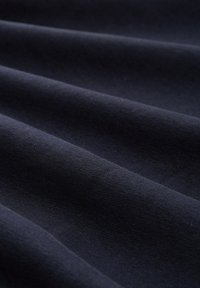 Tessuto blu navale dalla superficie liscia, che presenta onde e pieghe sottili, evidenziando l'intreccio uniforme e coerente in tutto il materiale.