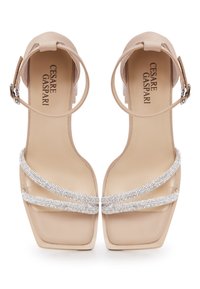 Sandales à talons nudes avec un bout carré et une bride de cheville, comportant deux brides en strass scintillants sur le dessus du pied. Texture en cuir lisse.