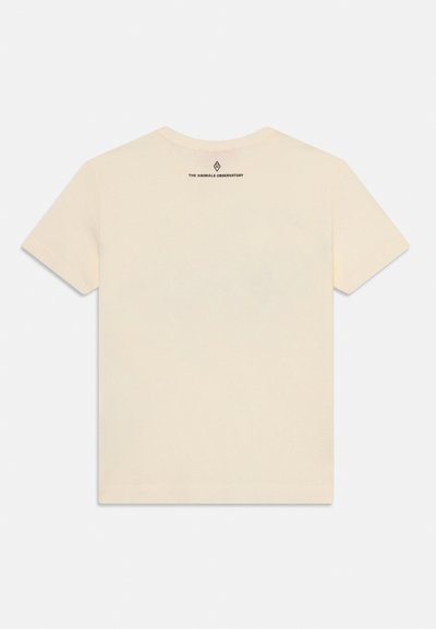 Camiseta de algodón color crema con mangas cortas. Presenta un escote redondo y un pequeño logo negro impreso en la parte superior de la espalda. Textura suave.