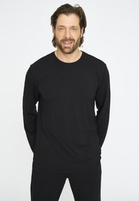 Sort langærmet T-shirt i et blødt, glat stof med rund halsudskæring; båret af en mand, parret med sorte bukser. Enkel design, afslappet stil.