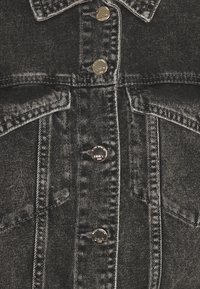 Černá denimová bunda zepředu se stříbrnými knoflíky označenými "ONLY 1995" a detailním prošíváním na kapsách a švech.